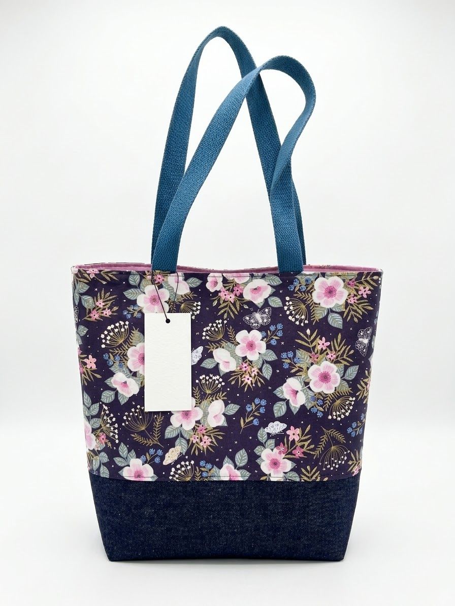 Large tote in a plum floral with pink blossoms, a dark denim base and blue handles